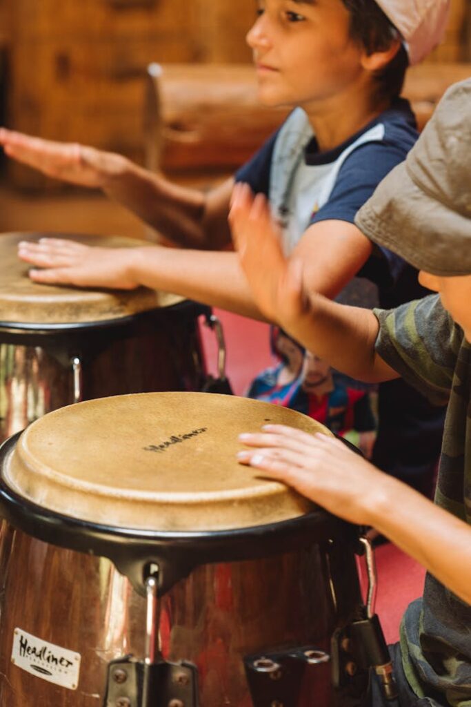 Two young children enthusiastically play hand drums, capturing the essence of joy and music indoors.